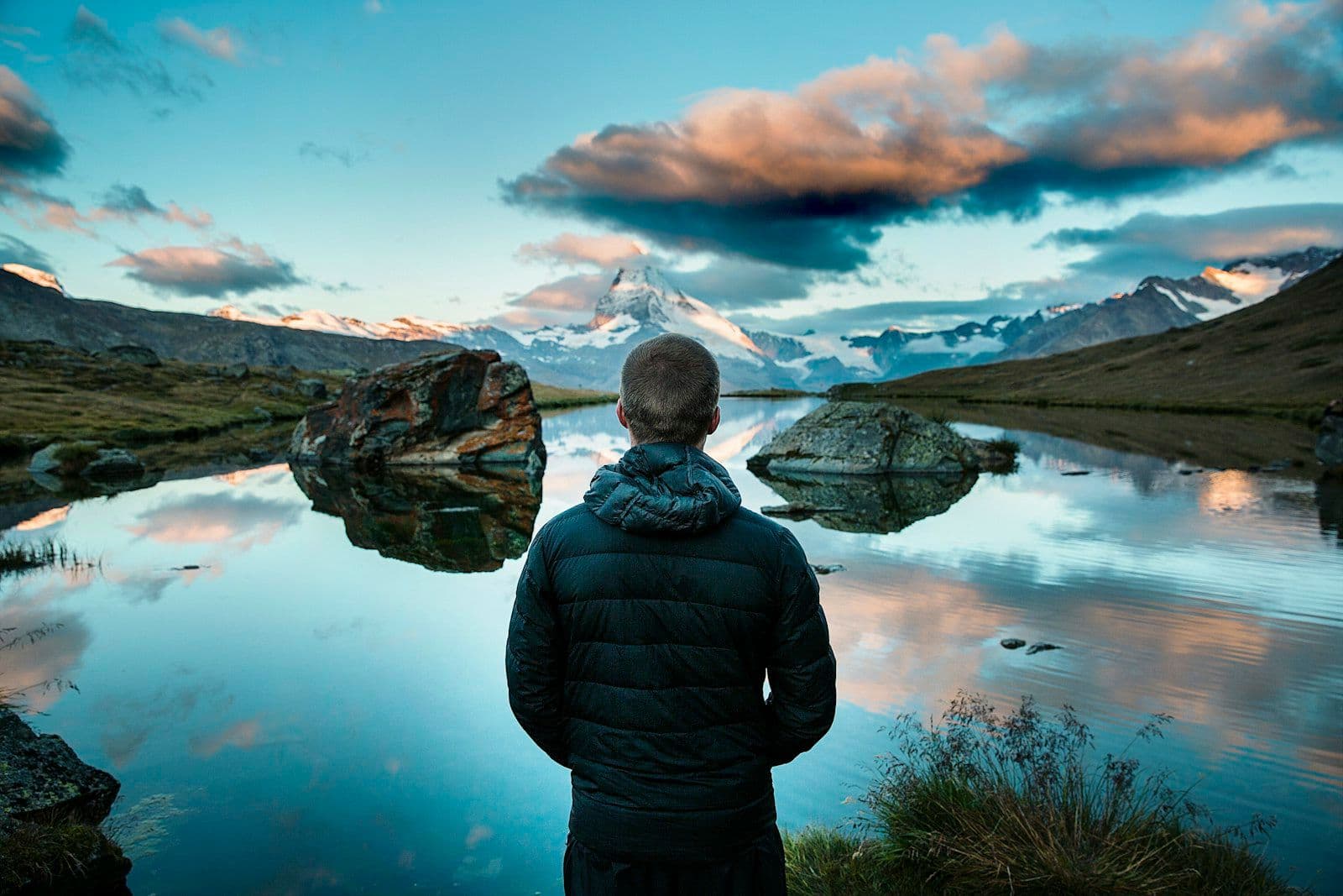 Eine Person blickt auf einen fernen Berg, der sich in einem See spiegelt