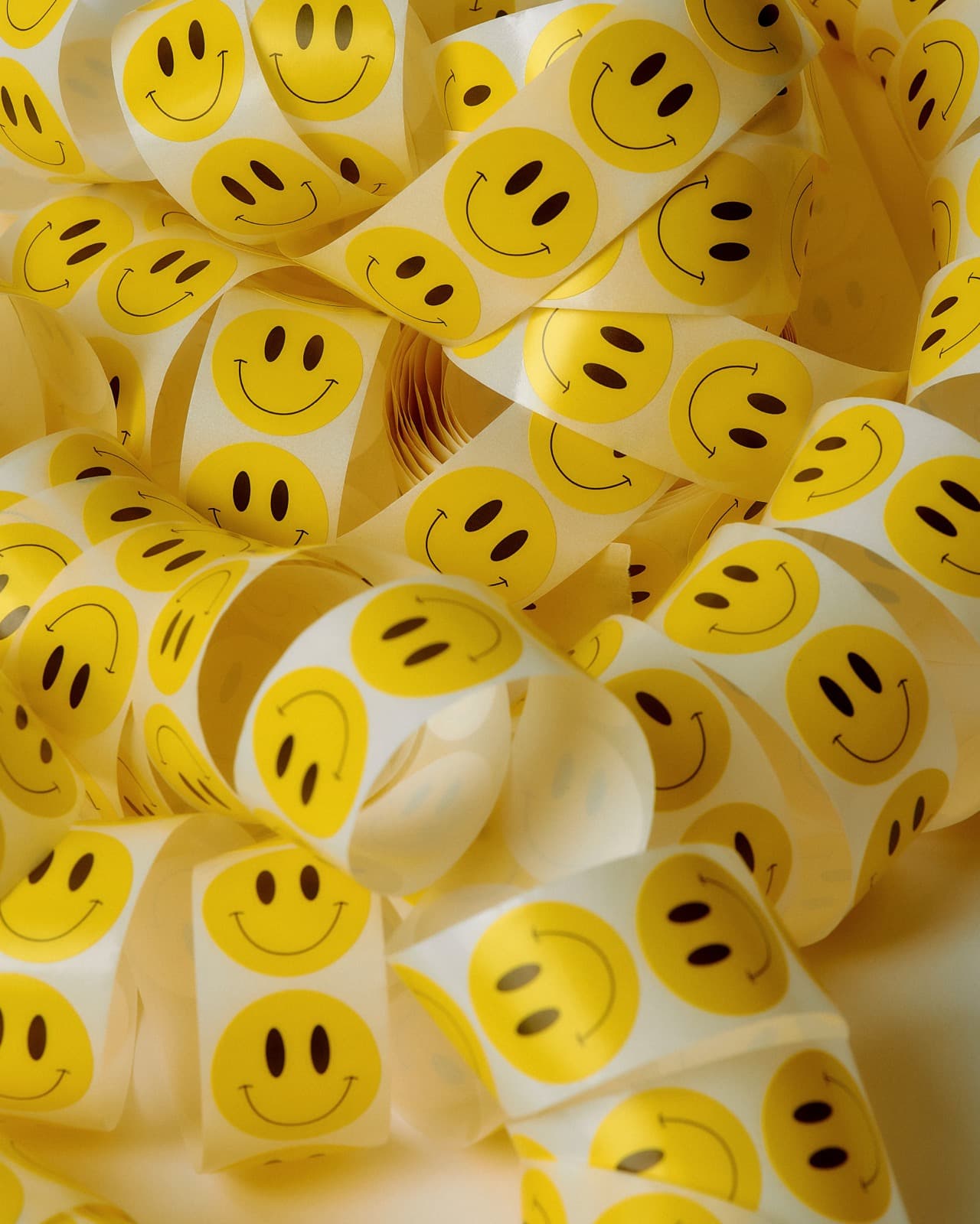 Curling strips of round smiley-face stickers piled loosely on top of one another